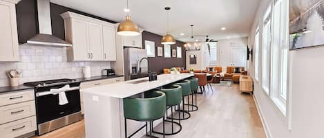 A modern kitchen with a central island, bar stools, and pendant lighting.