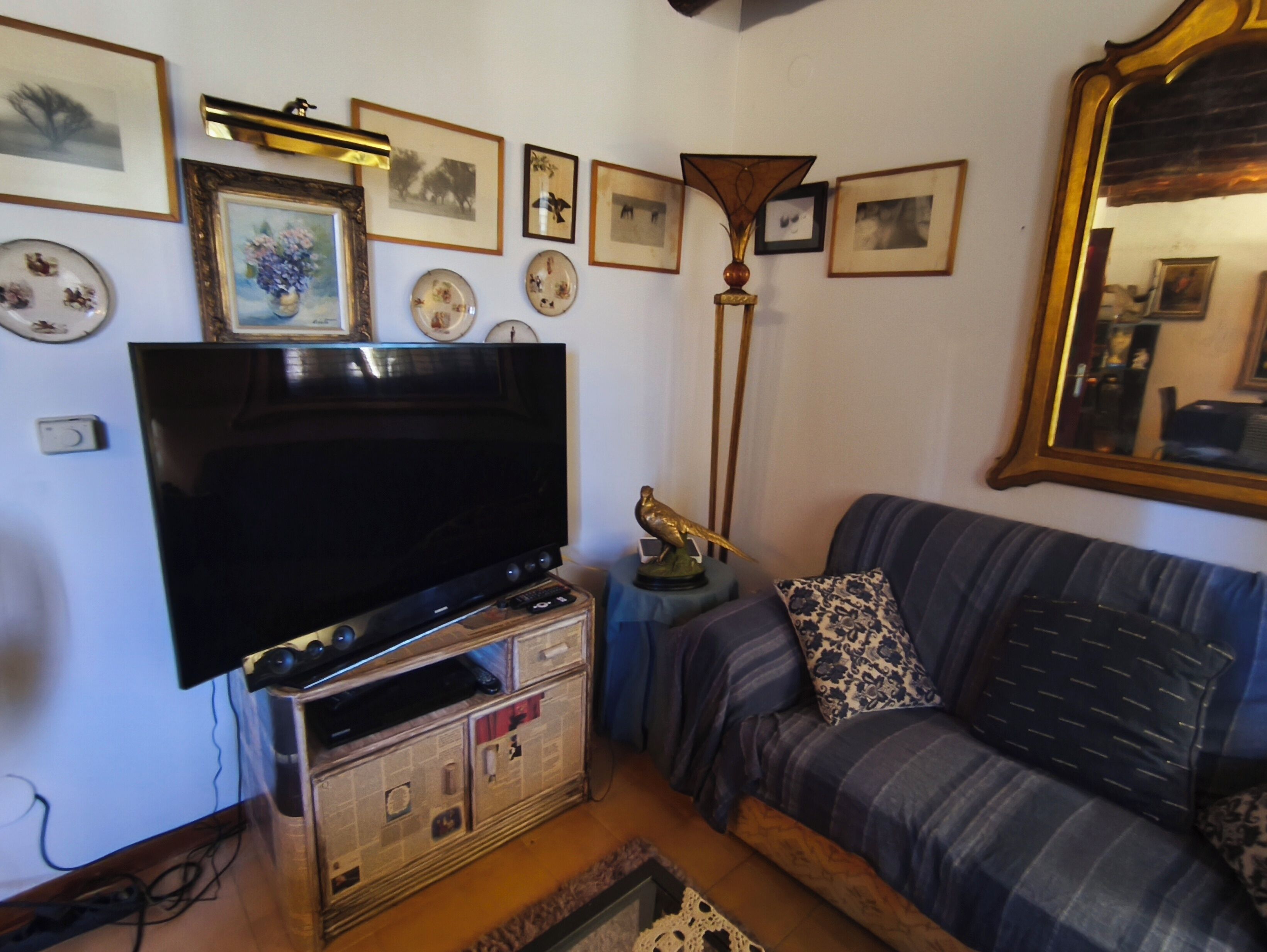 A living room with a flat-screen TV, a sofa, a coffee table, and various framed pictures on the wall.