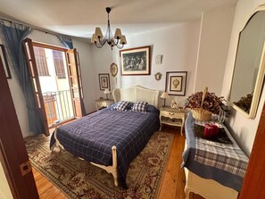 A bedroom with a bed, a nightstand, a dresser, a mirror, and a chandelier.