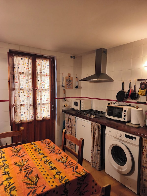 A compact kitchen with a washing machine, a microwave, and a stove.