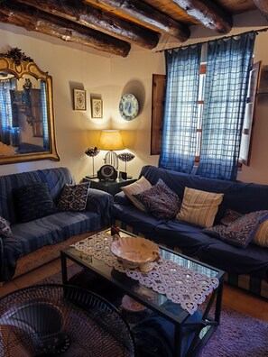 A cozy living room with a dark blue sofa, a glass coffee table, and a wooden ceiling.