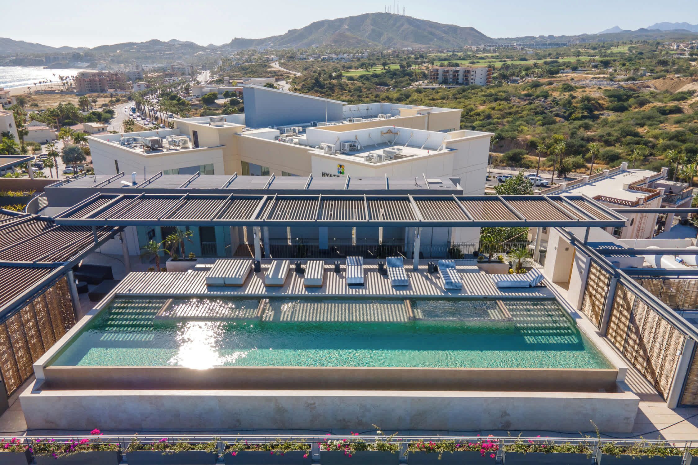 A rooftop pool with a clear view of the surrounding landscape, including hills and buildings.