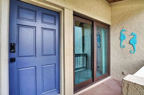 A blue door with a keypad lock, a glass door with a metal railing, and two seahorse decorations on the wall. - Sunset at Banyan Bay|Gulf-Front Condo on Longboat Key Beach+Pool+Tennis |Sleep 8 (Longboat Key)