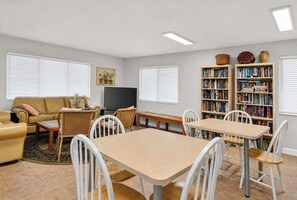 Un salon comprenant un canapé, un téléviseur, une table à manger, des chaises et une bibliothèque.