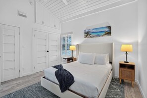 A hotel room with a bed, two bedside tables, a nightstand, a window with blinds, a picture on the wall, and a ceiling fan. - Sunset at Banyan Bay|Gulf-Front Condo on Longboat Key Beach+Pool+Tennis |Sleep 8 (Longboat Key)