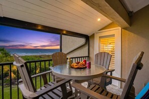 A balcony with a round table and chairs, overlooking a sunset view. - Sunset at Banyan Bay|Gulf-Front Condo on Longboat Key Beach+Pool+Tennis |Sleep 8 (Longboat Key)