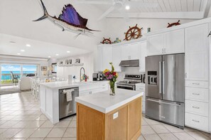 A modern kitchen with white cabinetry, stainless steel appliances, and a view to the ocean. - Sunset at Banyan Bay|Gulf-Front Condo on Longboat Key Beach+Pool+Tennis |Sleep 8 (Longboat Key)