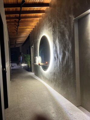 A hallway with a circular light fixture on a textured wall, a potted plant, and a small table with two white objects. - Luxury loft urban (Medellín)