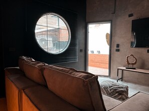 A modern living room with a large window, a sofa, and a small table with a decorative object. - Luxury loft urban (Medellín)