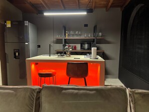 A compact kitchen with a central island, bar stools, and a refrigerator. - Luxury loft urban (Medellín)