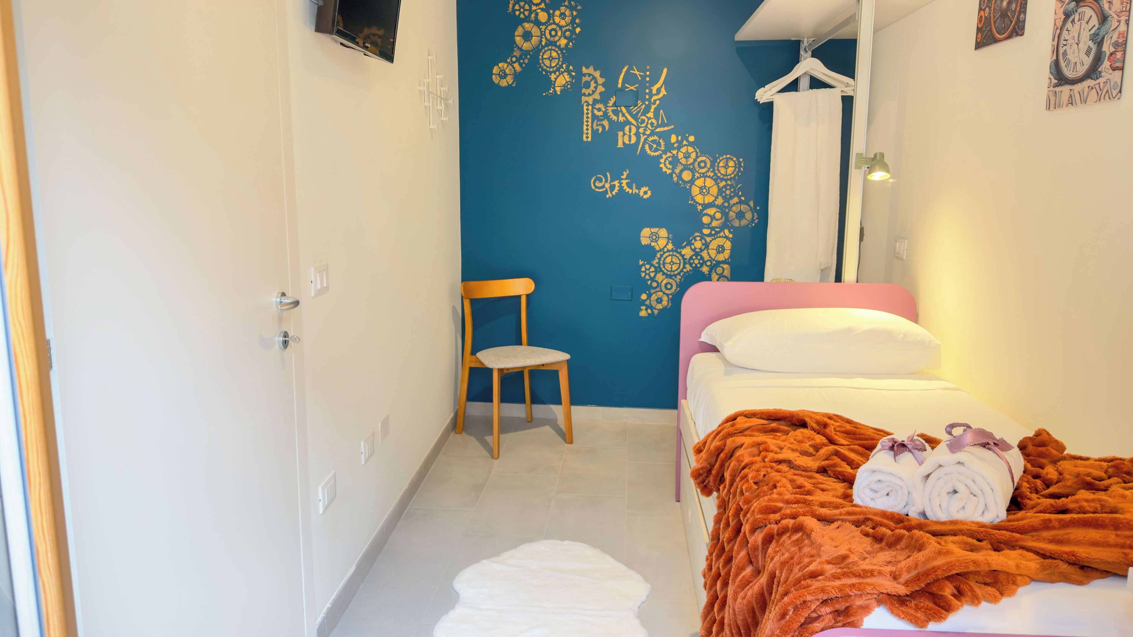 A bedroom with a bed, a chair, and a wall with a decorative design.