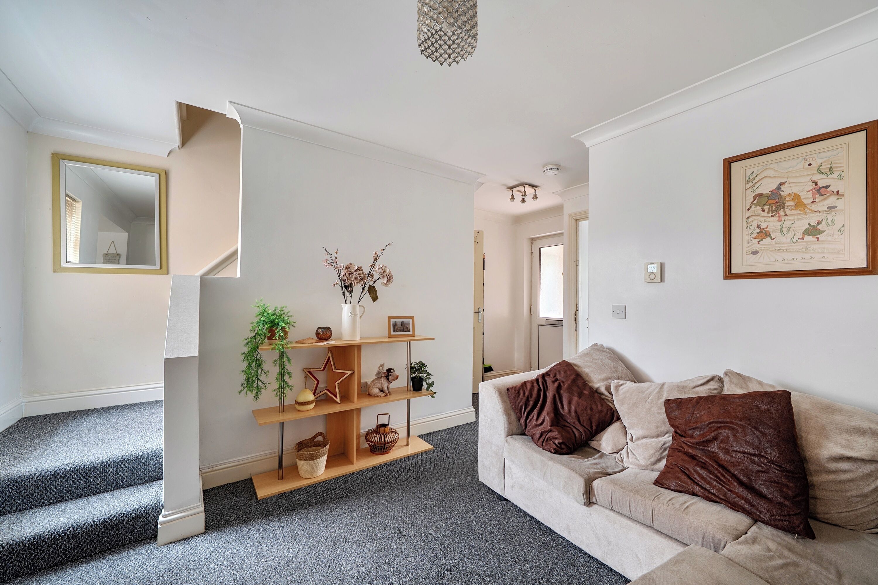 A living room with a sofa, a coffee table, and a fireplace. There is a staircase leading to another room.