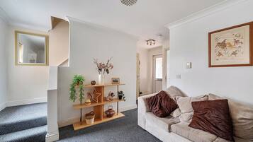 A living room with a sofa, a coffee table, and a fireplace. There is a staircase leading to another room.