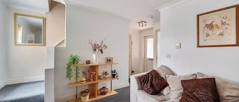 A living room with a sofa, a coffee table, and a fireplace. There is a staircase leading to another room.