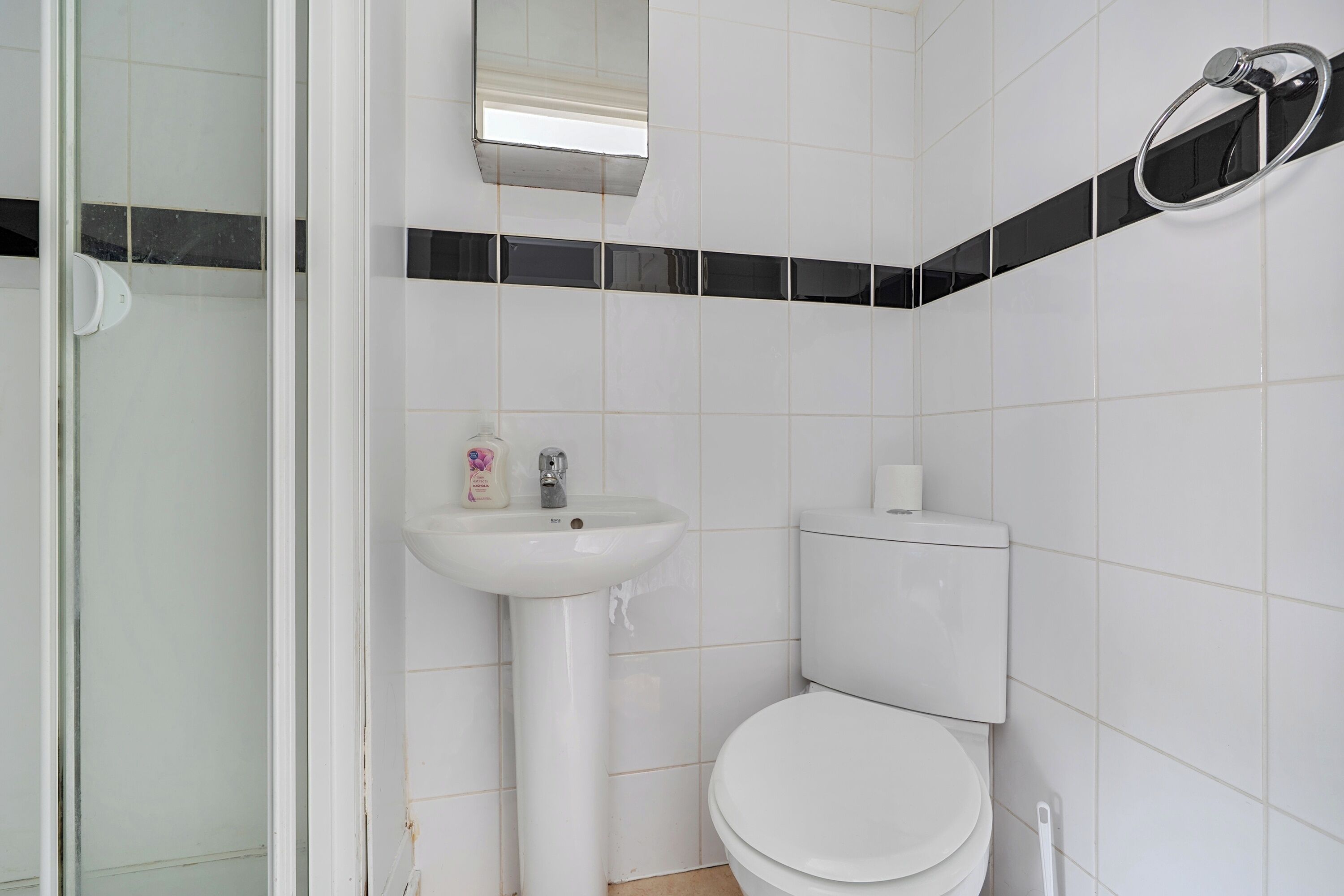 A bathroom with a white sink, toilet, and a glass shower door.