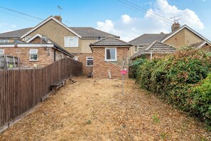 A residential area with houses, a wooden fence, and a dry lawn.