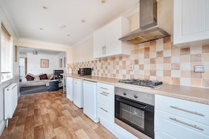A modern kitchen with white cabinetry, a tiled backsplash, a gas stove, and a built-in oven.
