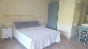 A bedroom with a bed, a nightstand, a wardrobe, and a chair. - Ginestre Smeraldo by Casa Check (Porto Rotondo)
