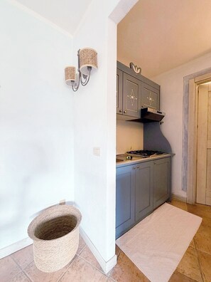 A kitchen with a gas stove, cabinets, and a hanging light fixture. - Mirto Smeraldo by Casa Check (Porto Rotondo)