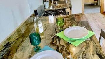 A marble dining table set with plates, cutlery, and glasses, with a kitchen in the background.