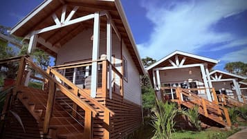 Two wooden cabins with external staircases, surrounded by greenery.