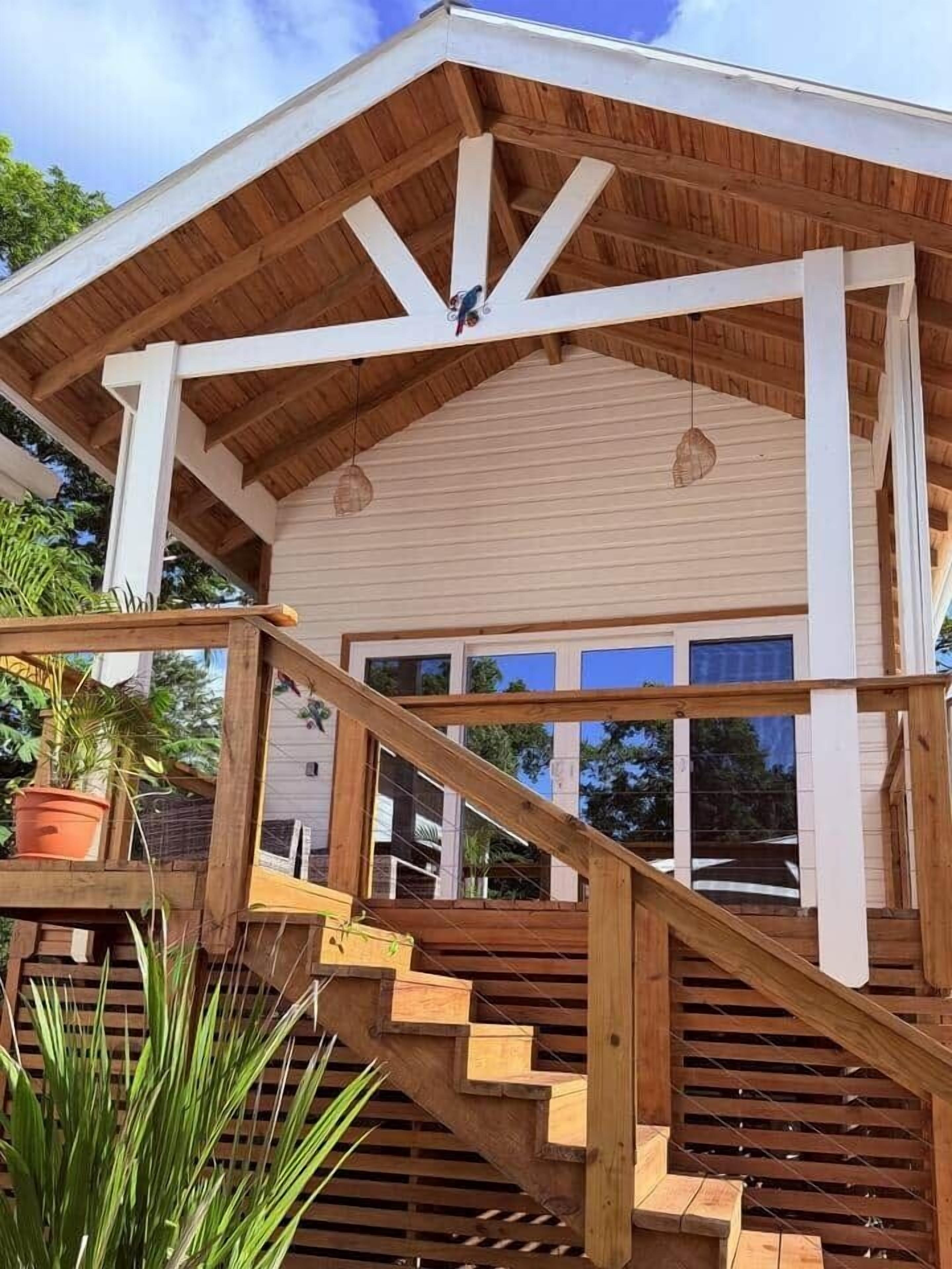 A wooden staircase leading to a covered porch with a white railing and potted plants.