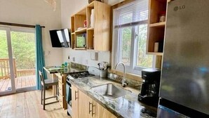 Eine Küche mit Holzausstattung, einem Edelstahlkühlschrank und einem Fenster mit Blick auf Grünflächen.