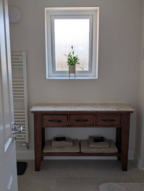A bathroom with a window, a towel rack, a sink, and a cabinet with drawers. - Cambridge Town House (Cambridge)
