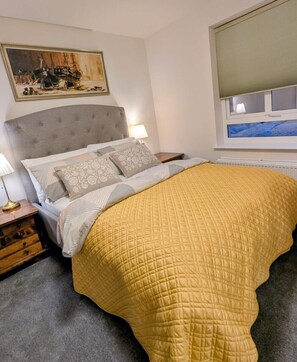 A bedroom with a bed, nightstands, a lamp, a painting, and a window. - Cambridge Town House (Cambridge)