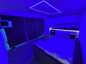 Ein modernes Schlafzimmer mit einem Bett, einem Nachttisch und einem an der Wand montierten Fernseher.