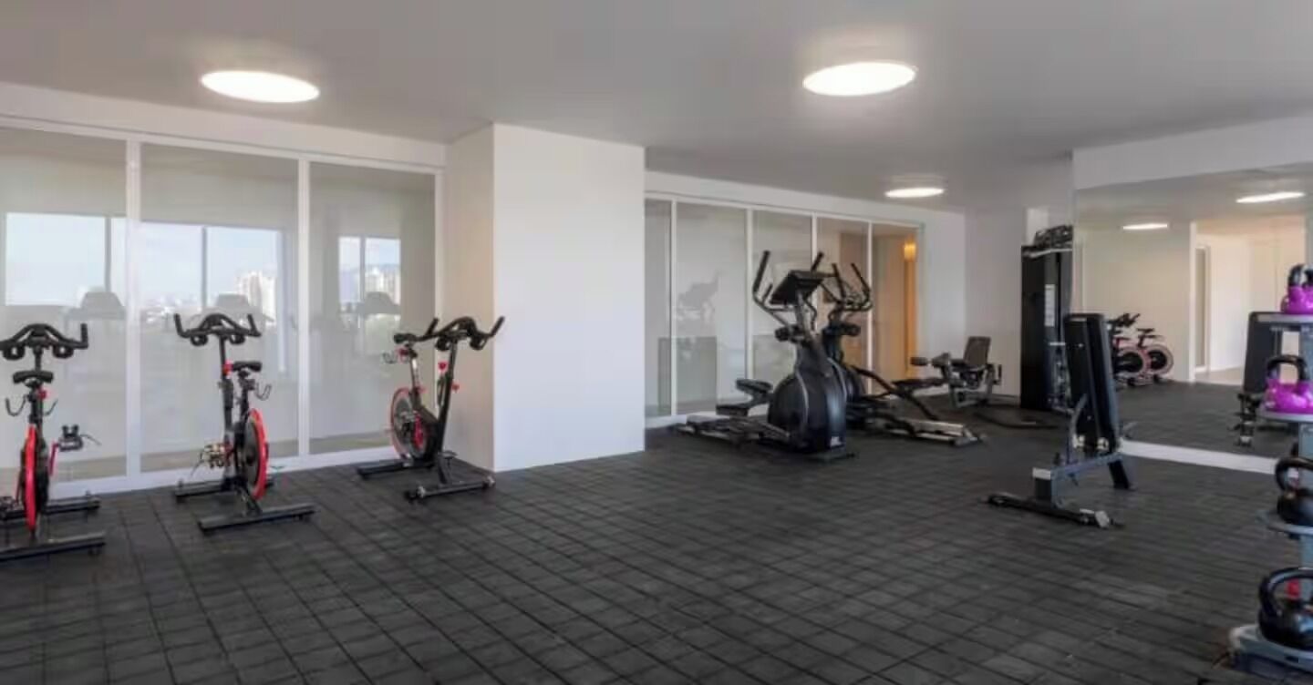Un gimnasio con bicicletas estáticas, elíptica y máquinas de pesas.
