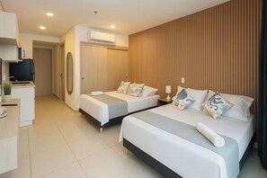 Ein Hotelzimmer mit zwei Betten, einem Schreibtisch, einem Fernseher und einer Wandklimaanlage.