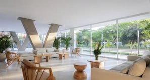 Ein modernes Interieur mit einer V-förmigen Decke, bequemen Sitzgelegenheiten und großen Fenstern mit Blick auf Grünflächen.