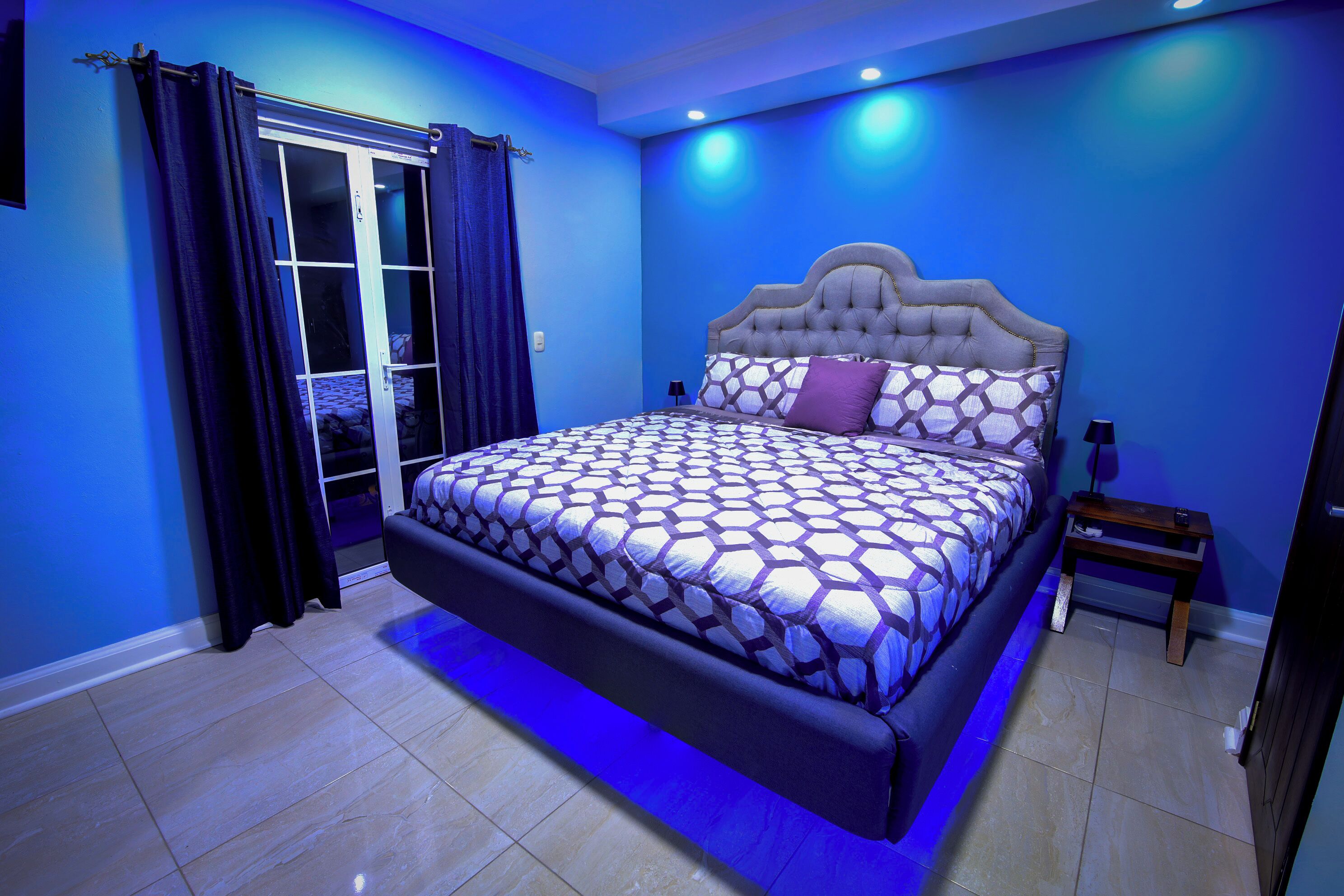 Een slaapkamer met een groot bed, een nachtkastje en een raam met gordijnen.
