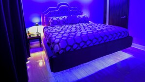 Un dormitorio con una cama grande, una mesita de noche y una puerta.