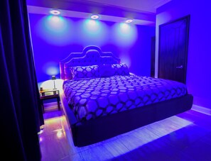 Un dormitorio con una cama grande, una mesita de noche y una puerta.