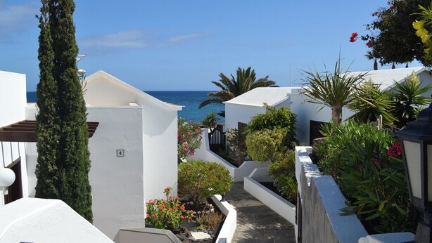 A coastal residential area with white buildings, a narrow pathway, and a view of the sea. - La Casita de la Playa – A Vacation Just a Few Steps from the Ocean (Playa Honda)
