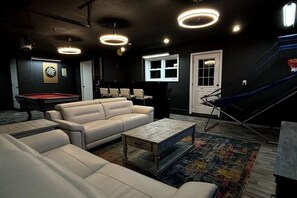 Una habitación con mesa de billar, sofá, mesa de centro y dardo.