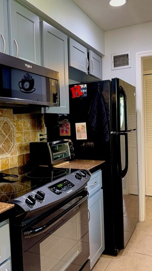 A kitchen with a stove, oven, microwave, and refrigerator. - Serene Escape. Tropical Gem. 
Cozy Chic Condo, 
Shared space Pvt. Bed/Bath w AC (Eustis)