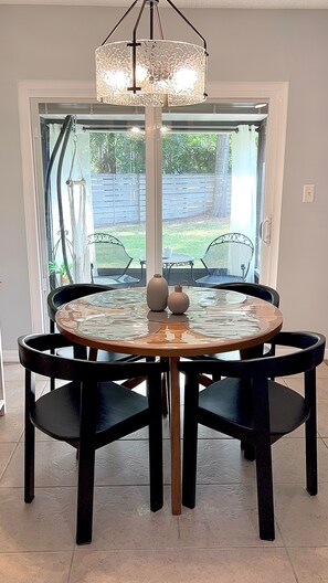 A round dining table with chairs, a chandelier, and a view of the outdoors. - Serene Escape. Tropical Gem. 
Cozy Chic Condo, 
Shared space Pvt. Bed/Bath w AC (Eustis)