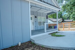Een woonhuis met een overdekte veranda, een voordeur en een kleine voortuin.