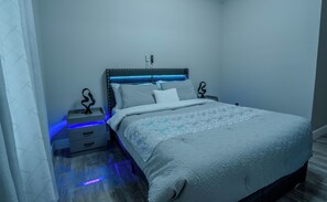 Un dormitorio con cama, mesitas de noche y teléfono en la pared.
