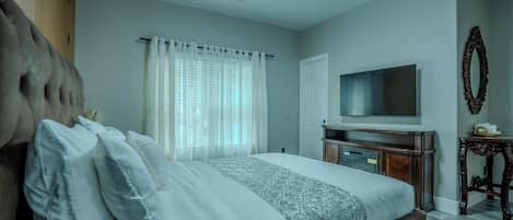 Un dormitorio con cama, televisor y espejo.
