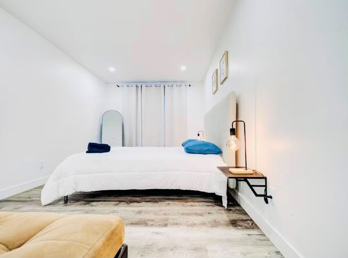 Ein Schlafzimmer mit einem Bett, Nachttisch, Lampe und Spiegel.