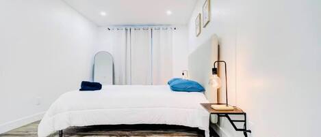Une chambre à coucher avec un lit, une table de chevet, une lampe et un miroir.