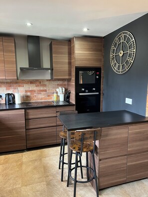 Eine moderne Küche mit Holzausstattung, einem eingebauten Backofen und einer großen Wanduhr.
