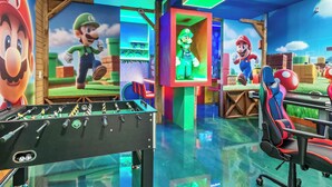 Una habitación luminosa con una mesa de fútbol de mesa, sillas de juego y decoración temática de Mario.