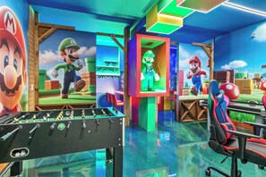 A brightly lit room with a foosball table, gaming chairs, and Mario-themed decorations. - Luxury 8BR Themed Villa with Private Pool (Clermont)