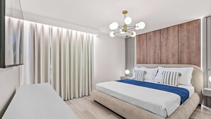 Un dormitorio moderno con una cama grande, una mesita de noche, una lámpara colgante y vistas al exterior.