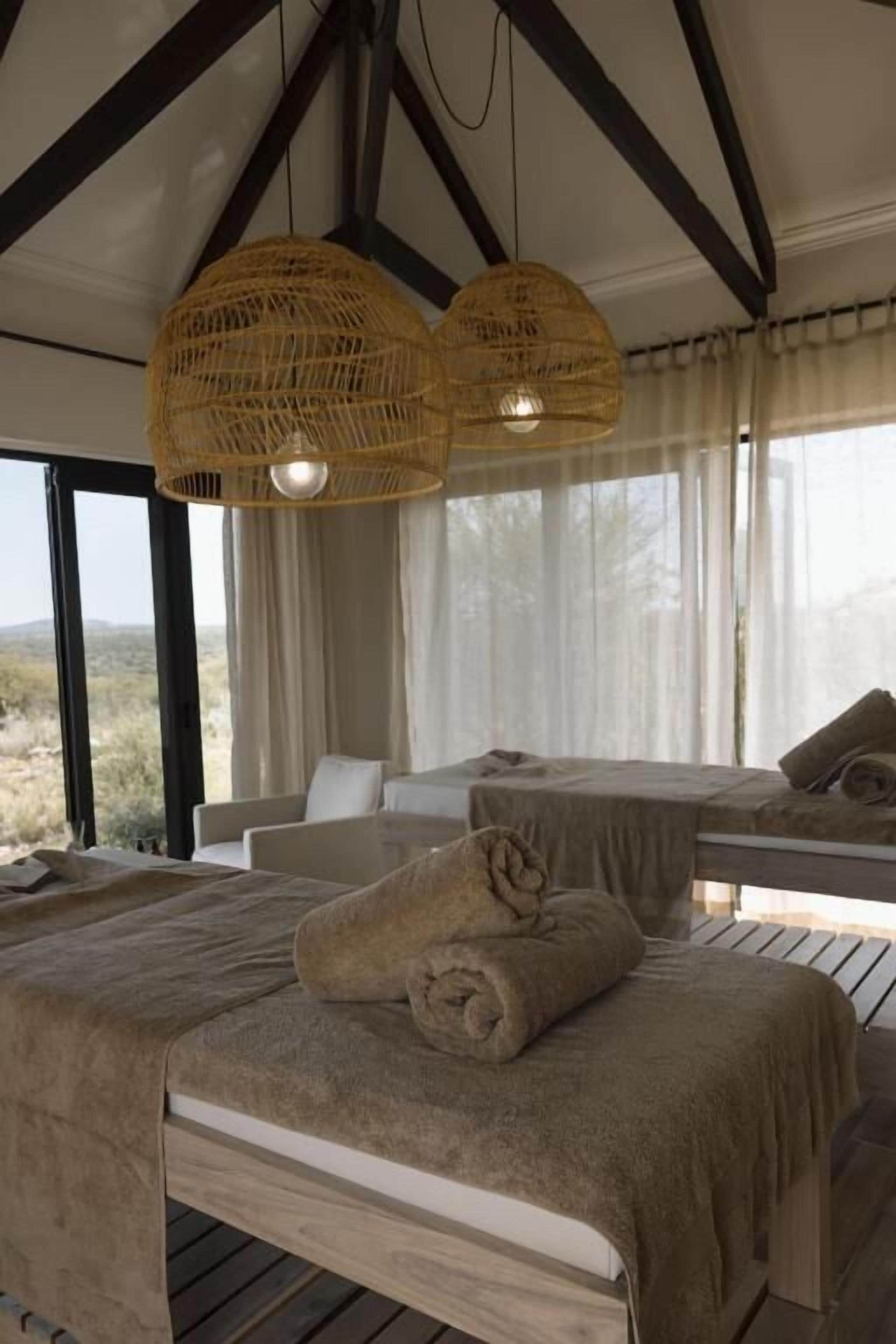 A room with two beds, a sofa, and a table. There are wicker lamps hanging from the ceiling.